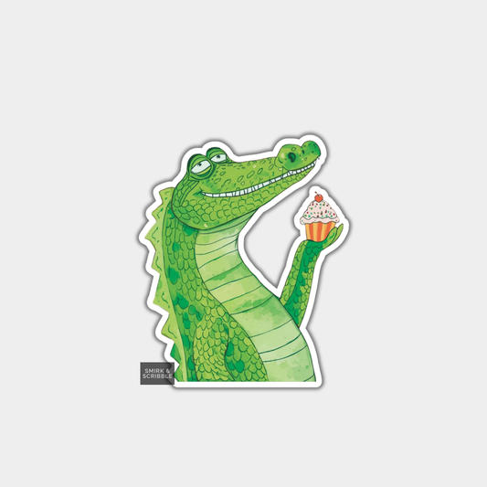 Sticker of a green crocodile holding a cupcake on a gray background